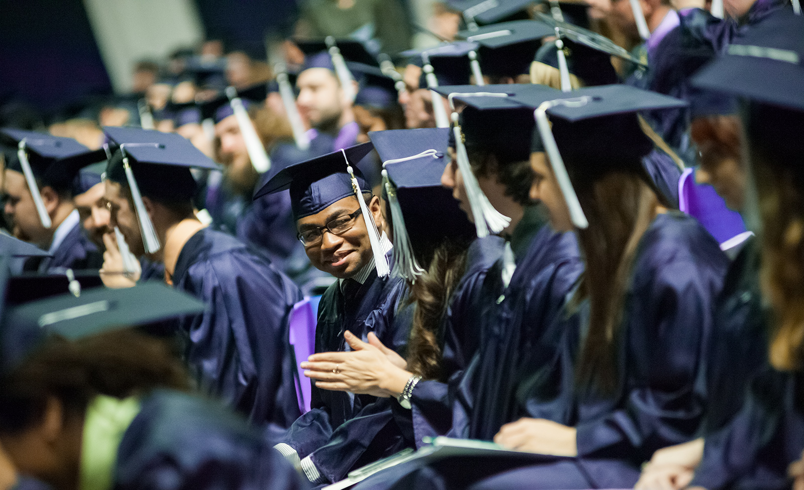 A Penn State graduate smiles at his peers during the commencement ceremony
